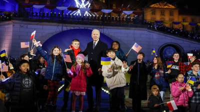 Джо Байдън стои на сцената с деца които държат знамена