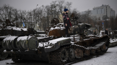 Момче стои върху изваден от строя руски танк изложен на