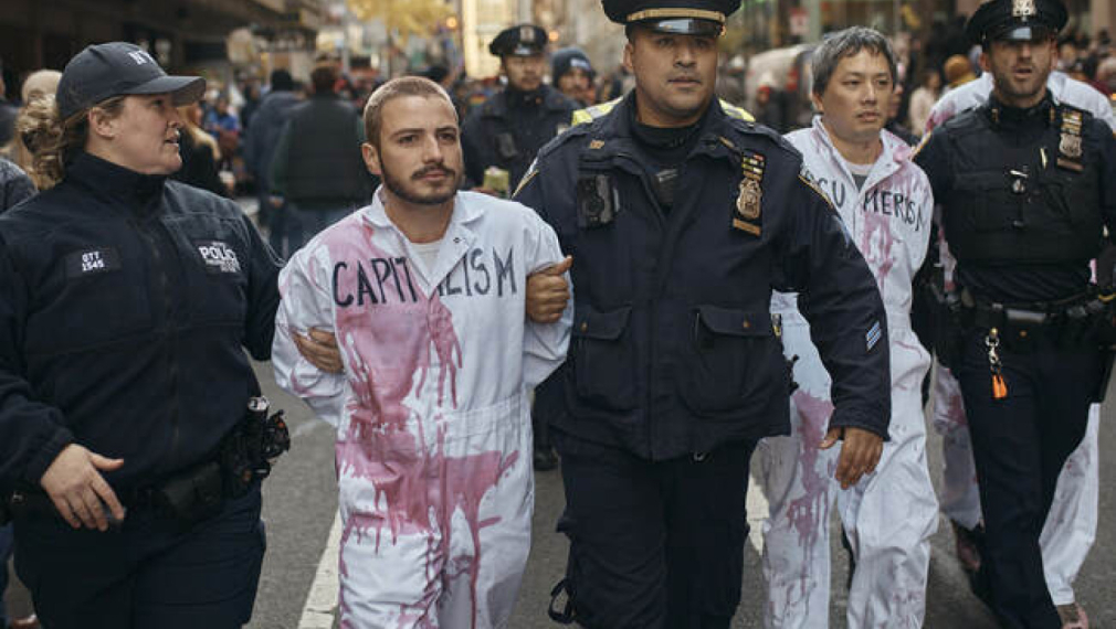 Полицаи отвеждат арестувани пропалестински демонстранти, оплискани с фалшива кръв, които