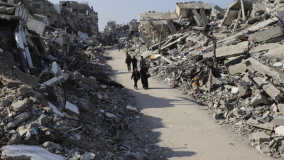 Палестинци вървят предз разрушения при израелски бомбардировки бежански лагер Джабалия